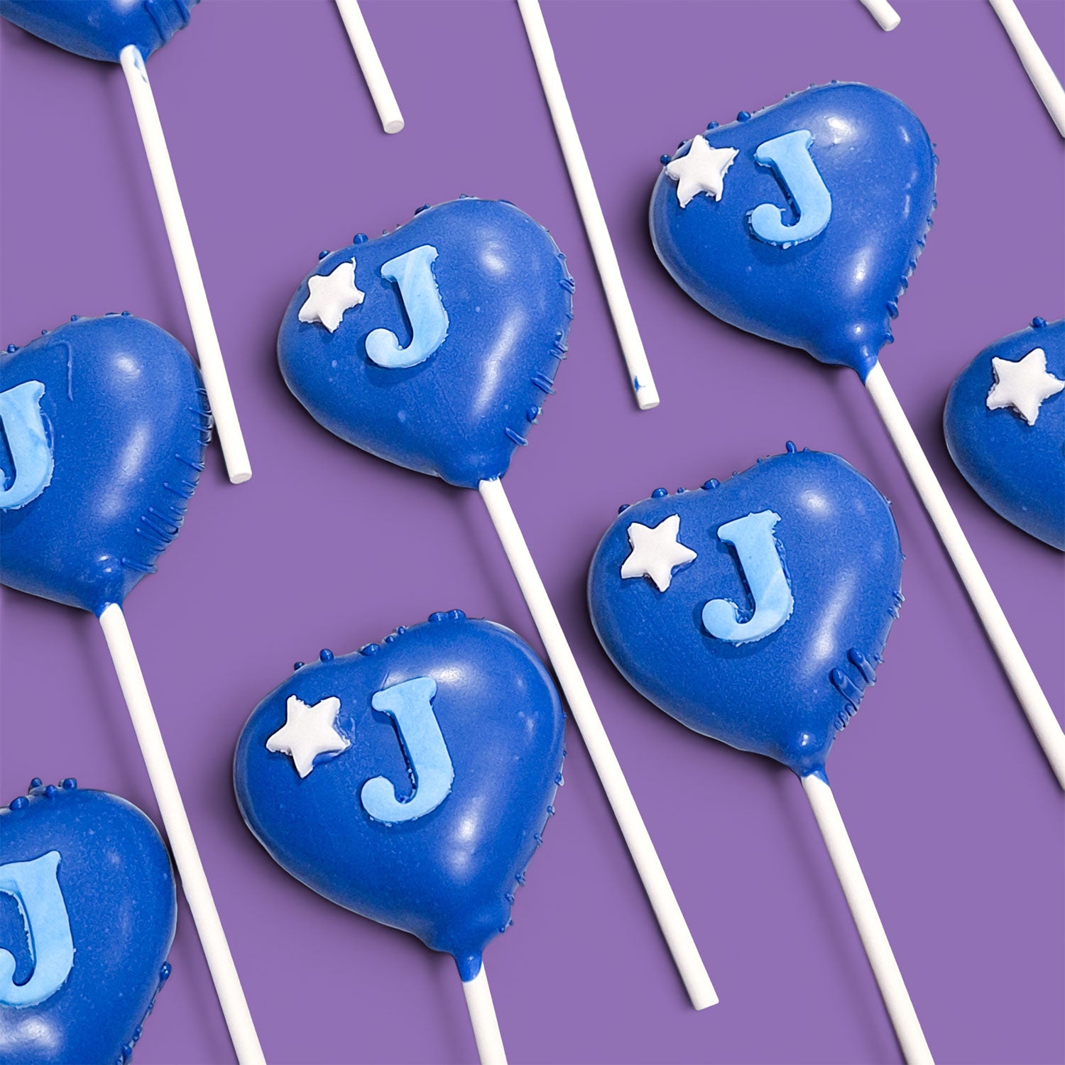 Blue heart-shaped Cake Pops with 'J' and white stars.