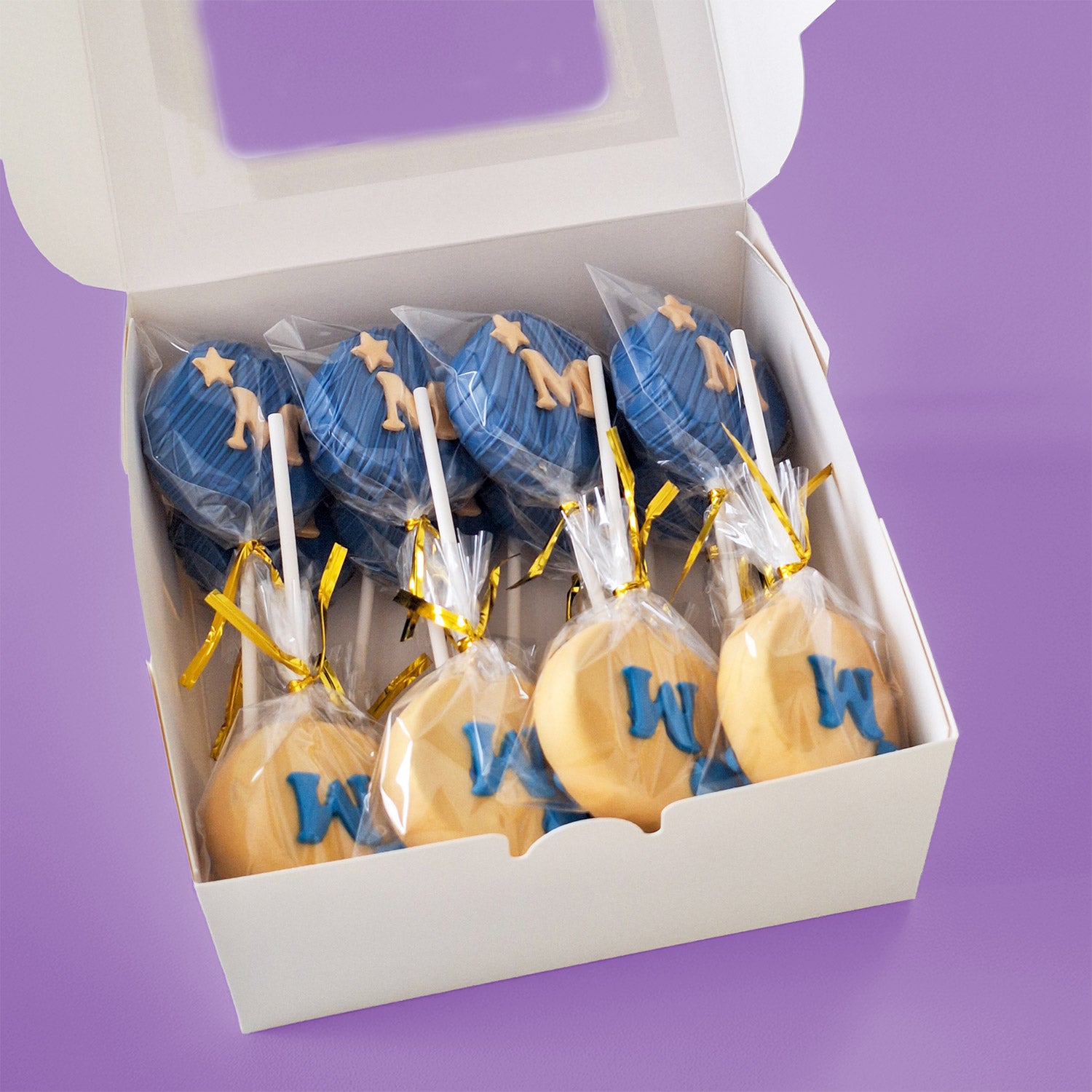 Box of Blue and Gold Cake Pops with letter 'M' and stars.