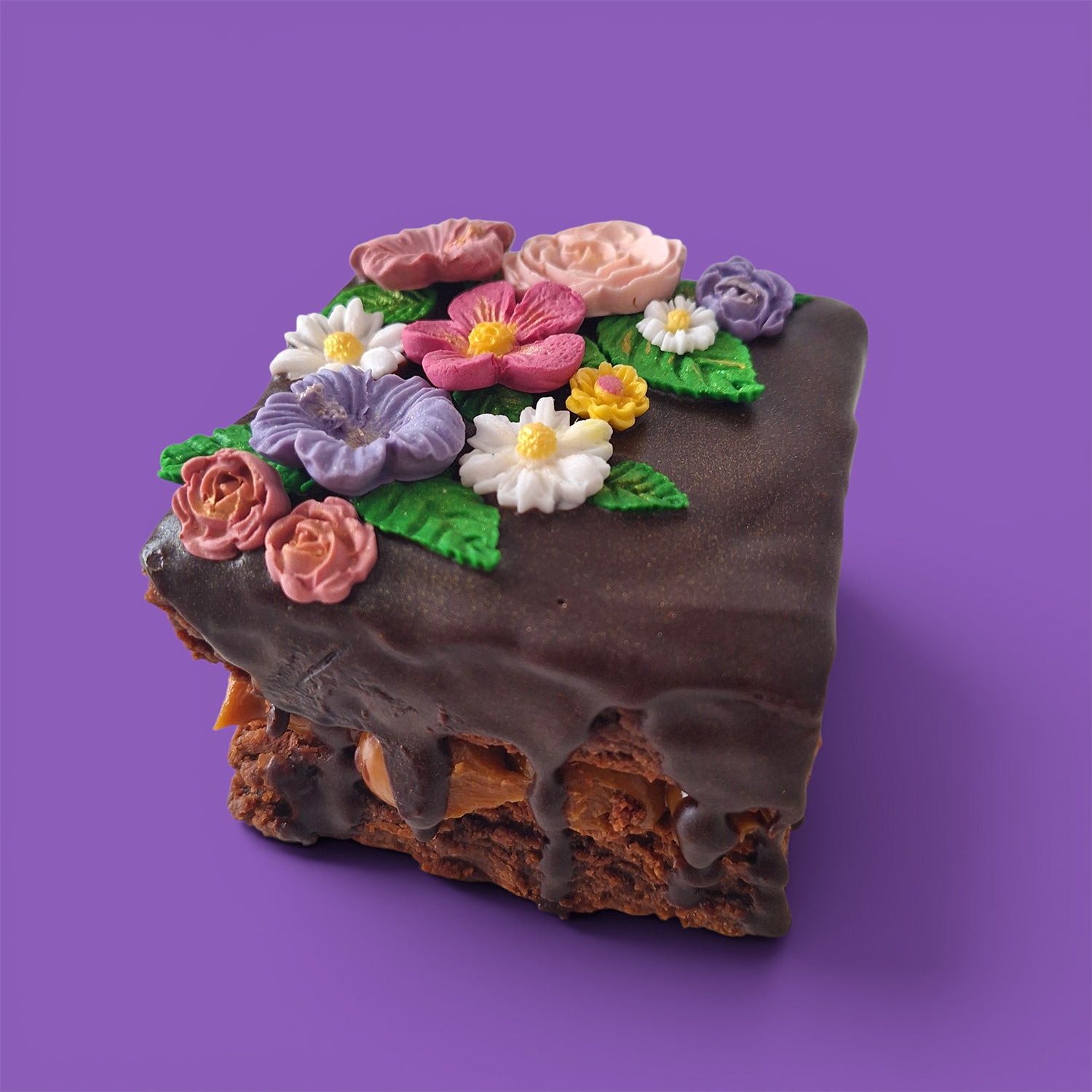 Brownie cake and caramel with colourful flower decorations on a chocolate sauce