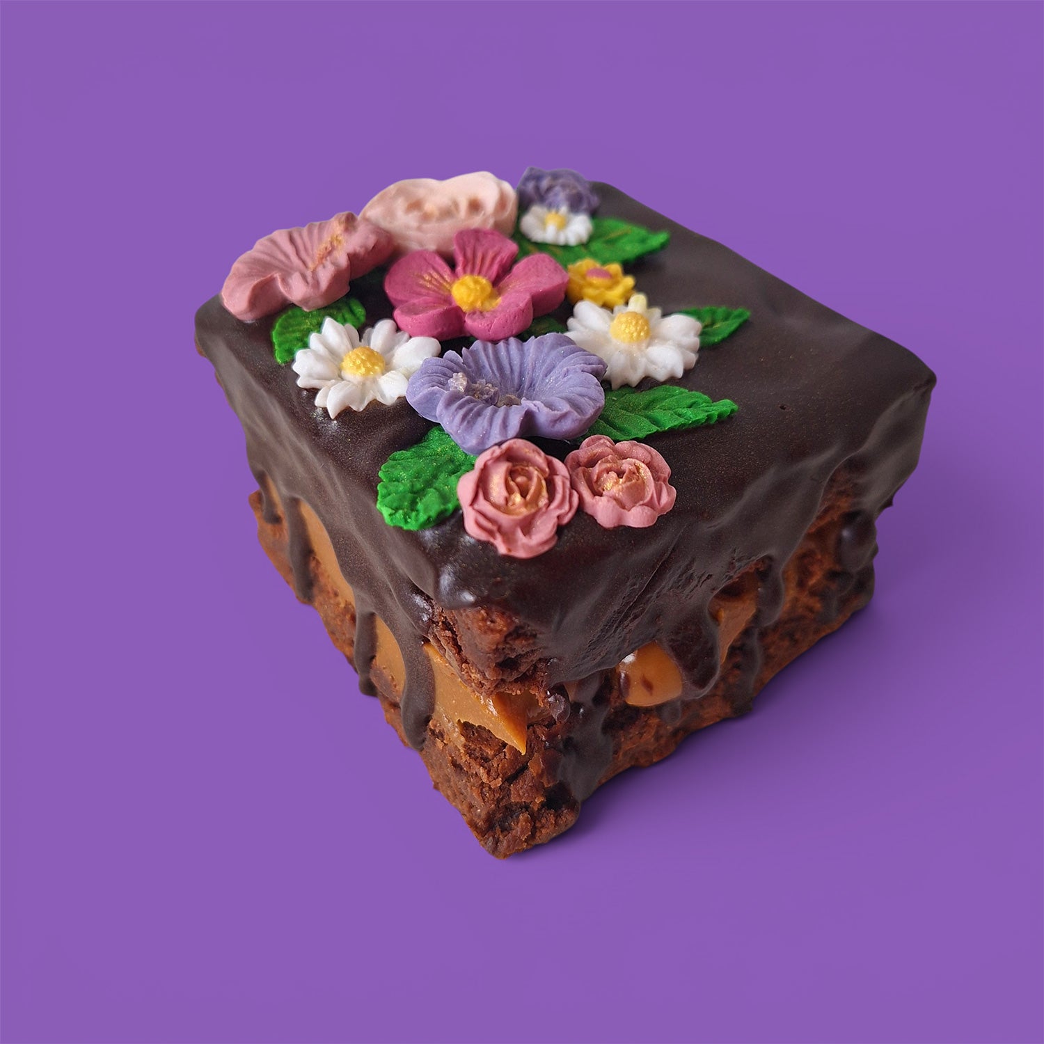 Brownie cake and caramel with colourful flower decorations on a chocolate sauce front view