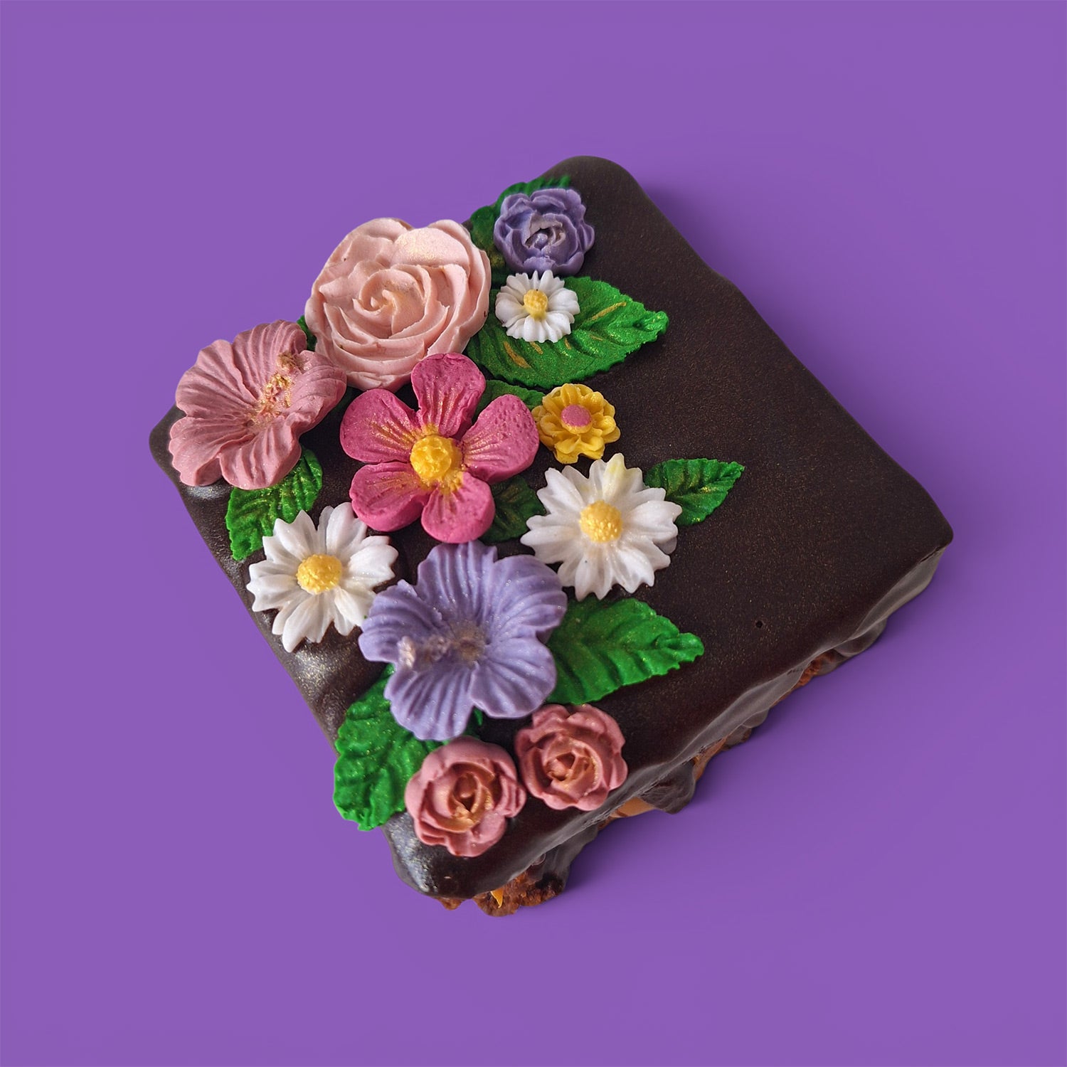 Brownie cake and caramel with colourful flower decorations on a chocolate sauce top view.