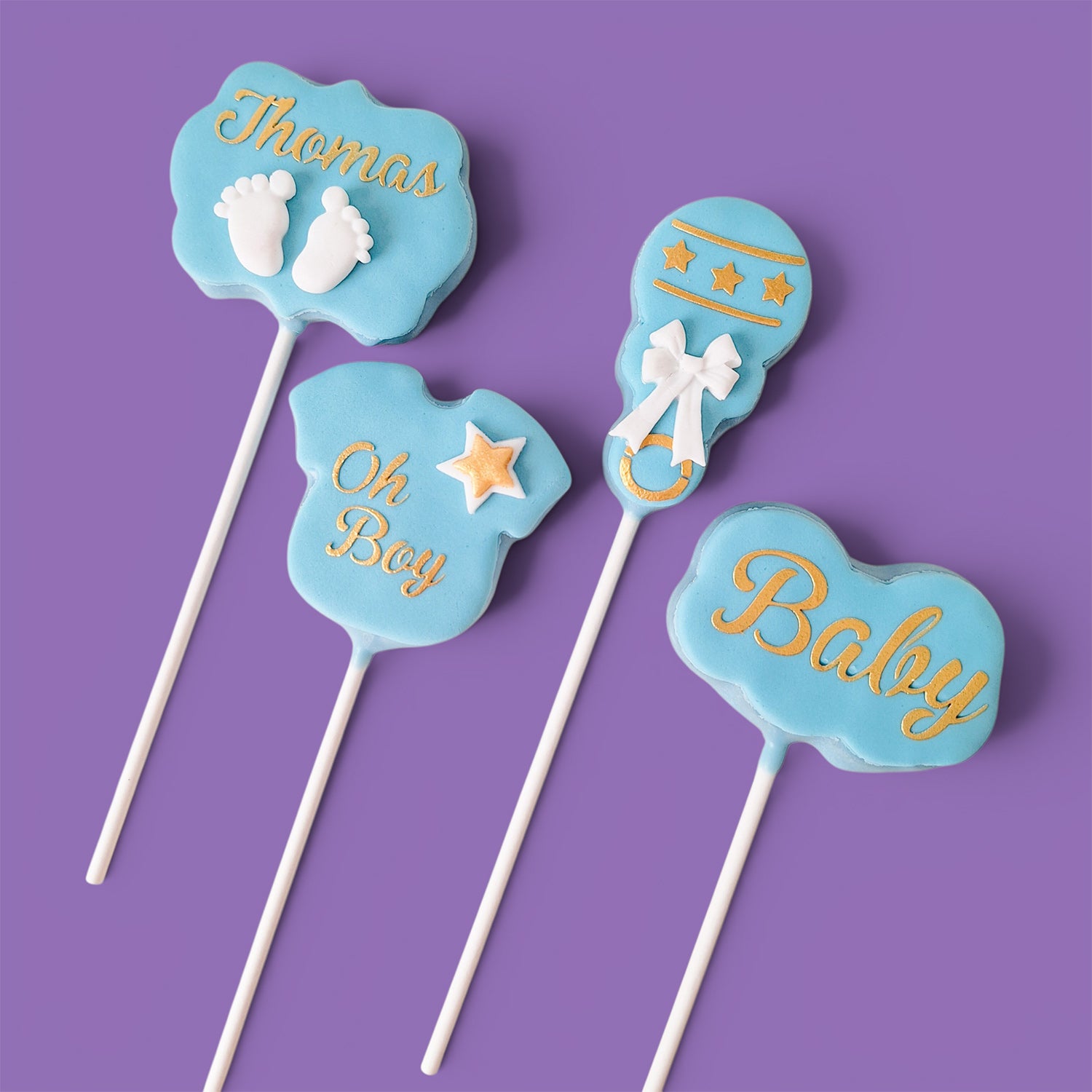 Four Cake Pops with baby boy shower themed text and designs.