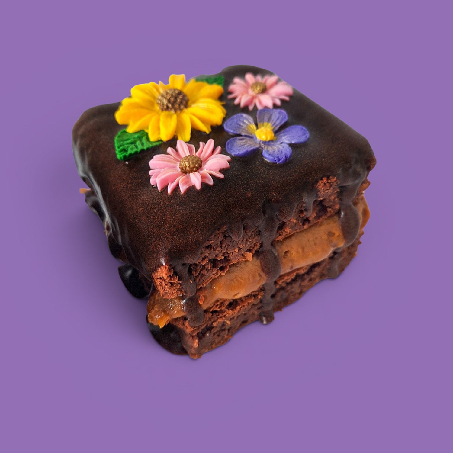 Option 2 Brownie cake and caramel with colourful flower decorations on a chocolate sauce side view.