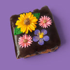Option 2 Brownie cake and caramel with colourful flower decorations on a chocolate sauce top view.