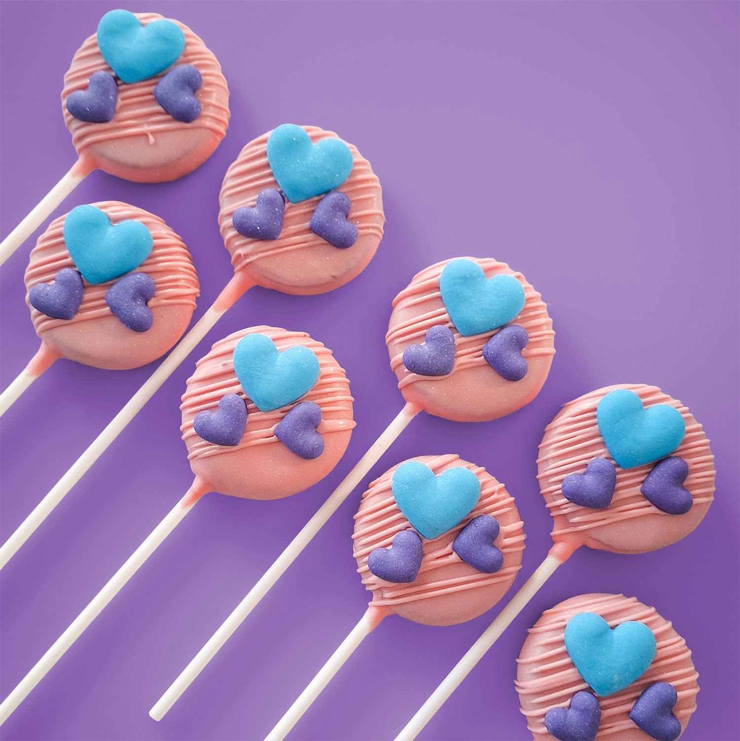 Pink Rounded Cake Pops with blue and purple heart decorations.