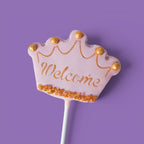 Third Cake Pops with baby girl shower themed text "Welcome" and crown designs.