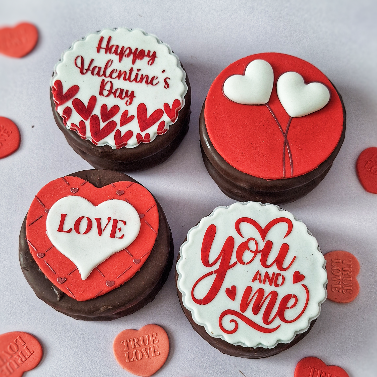 Valentine's Day-themed cookies with red and white icing on a light gray background.